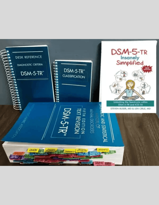 Three DSM-5-TR reference books in blue bindings and one smaller white study guide are displayed on a wooden surface, with the thickest book featuring several multicolored index tabs along its pages.